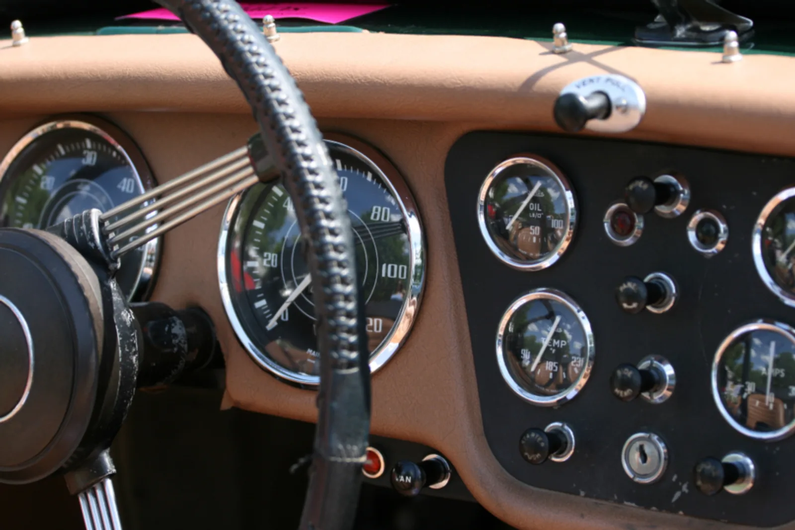 A classic car dashboard with a wood-rim steering wheel