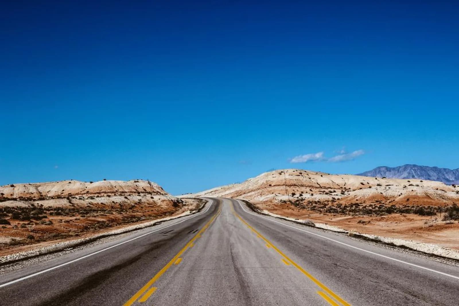 A straight desert highway under a blue sky