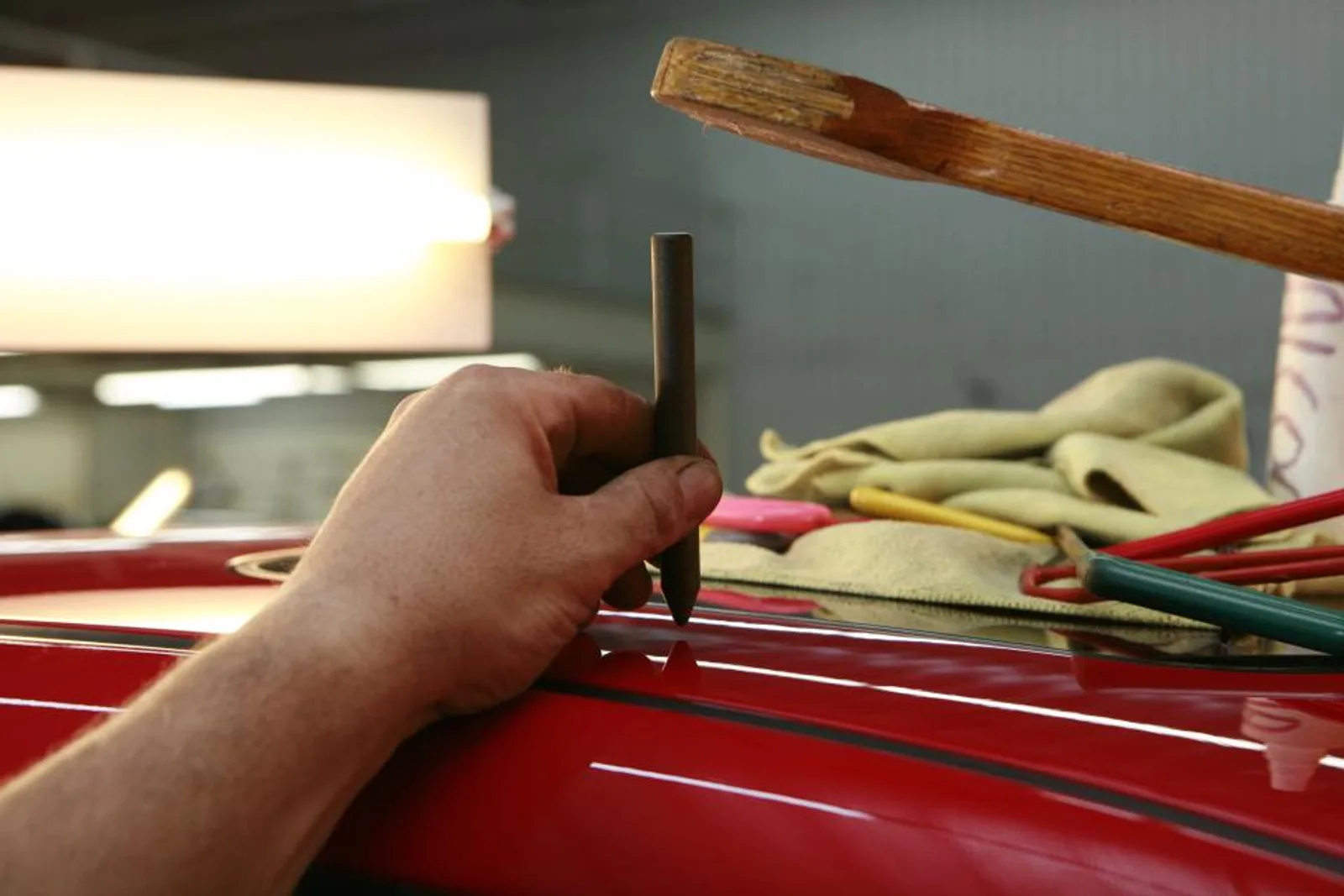 A mechanic's hand working on a red car